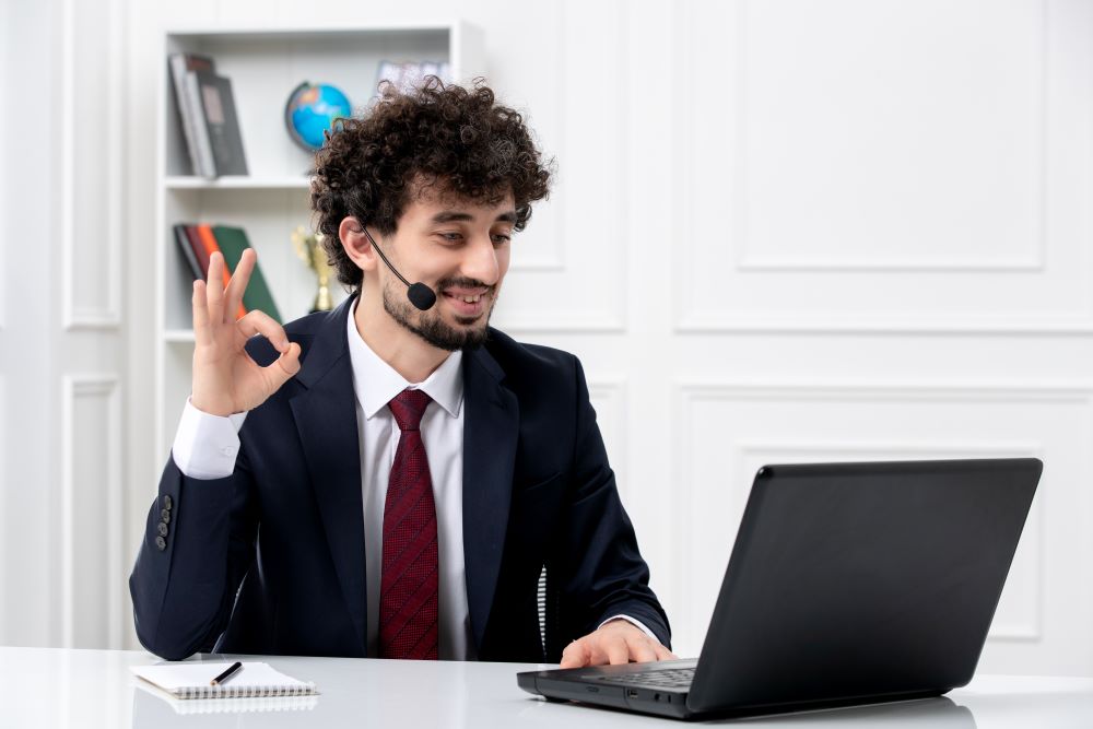 customer service handsome young guy office suit with laptop headset showing ok gesture