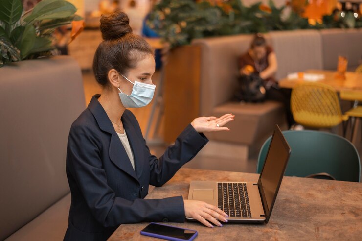 side view businesswoman with medical mask working her laptop